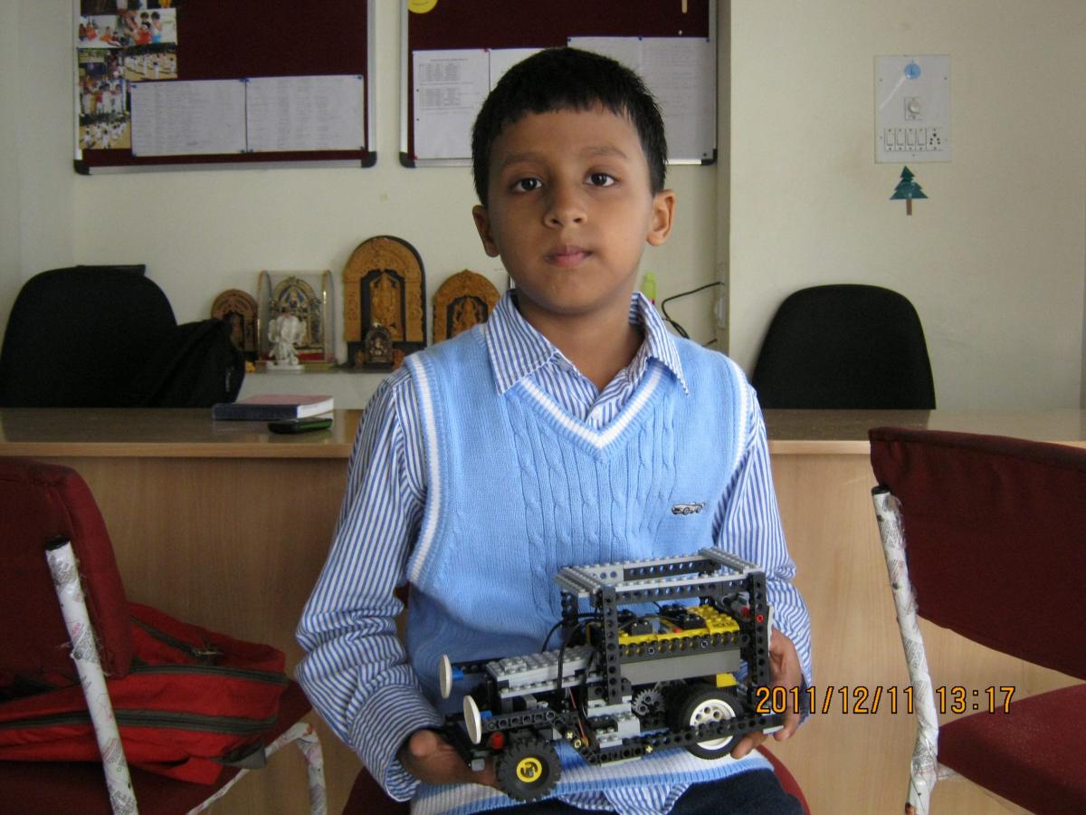 Me as a child, holding a wheeled robot built from construction pieces.